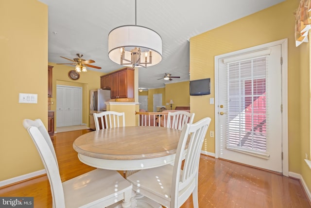 dining room featuring ceiling fan with notable chandelier, baseboards, and light wood-style floors