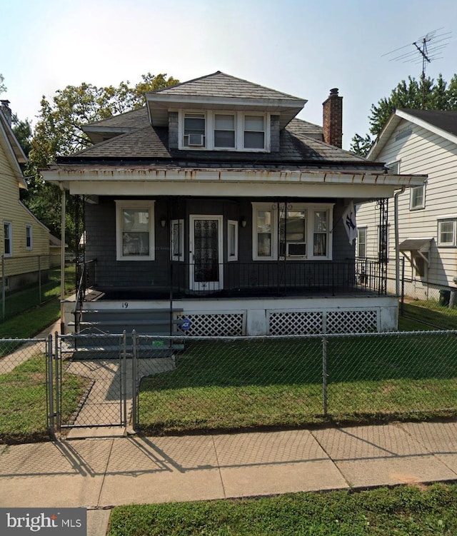 bungalow-style home with a fenced front yard, a chimney, a porch, a gate, and a front lawn