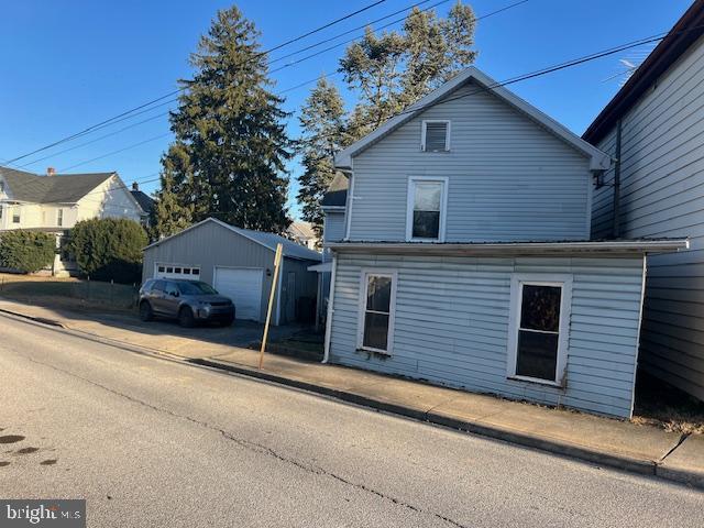 view of front of home with a detached garage and an outbuilding