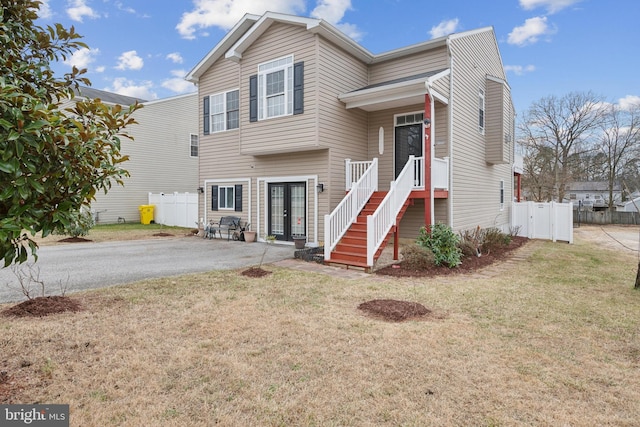 tri-level home with a patio area, aphalt driveway, fence, and a front lawn