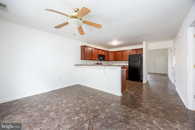 kitchen with black appliances, a kitchen breakfast bar, a peninsula, and baseboards