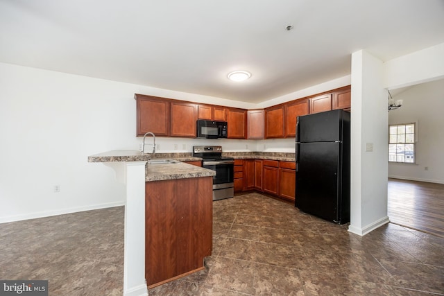 kitchen with baseboards, a peninsula, a sink, black appliances, and a kitchen breakfast bar