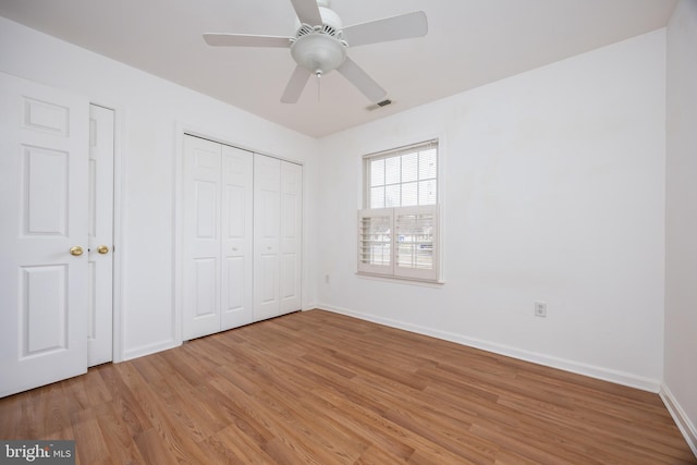 unfurnished bedroom featuring a ceiling fan, baseboards, visible vents, a closet, and light wood-type flooring