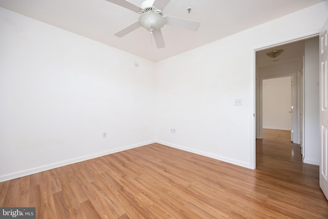 spare room featuring a ceiling fan, baseboards, and light wood finished floors