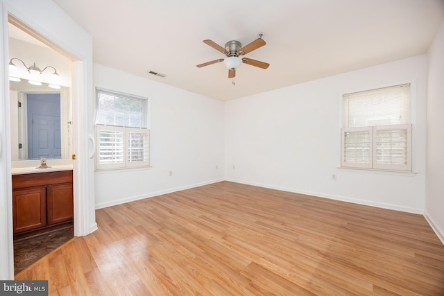 unfurnished bedroom with visible vents, a ceiling fan, connected bathroom, light wood finished floors, and baseboards