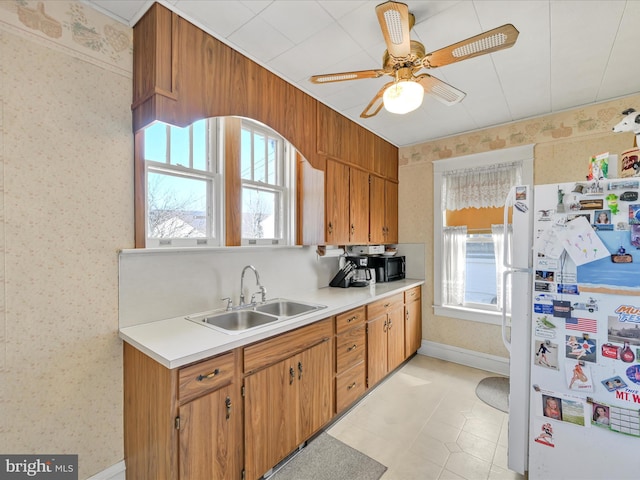 kitchen featuring light countertops, a sink, freestanding refrigerator, and wallpapered walls