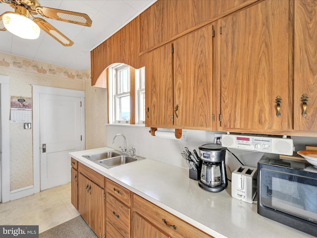 kitchen with black microwave, light countertops, a sink, and wallpapered walls