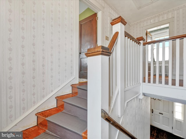 staircase featuring baseboards, wood finished floors, and wallpapered walls