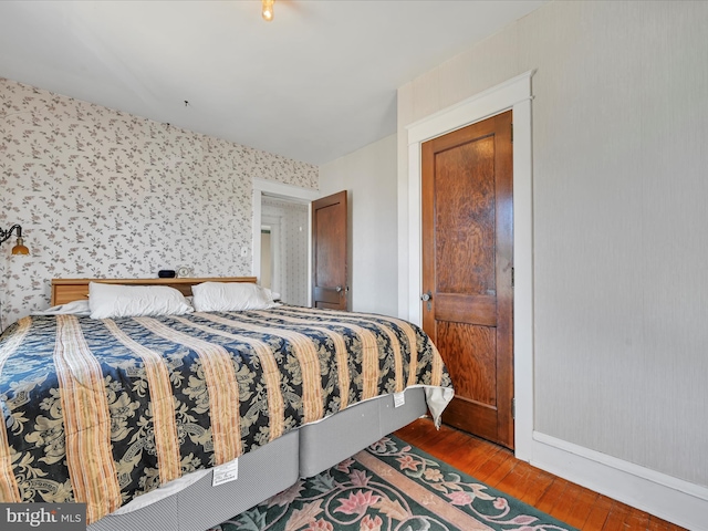 bedroom featuring wood finished floors and wallpapered walls