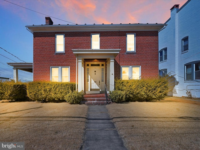 view of front of property with brick siding and a chimney