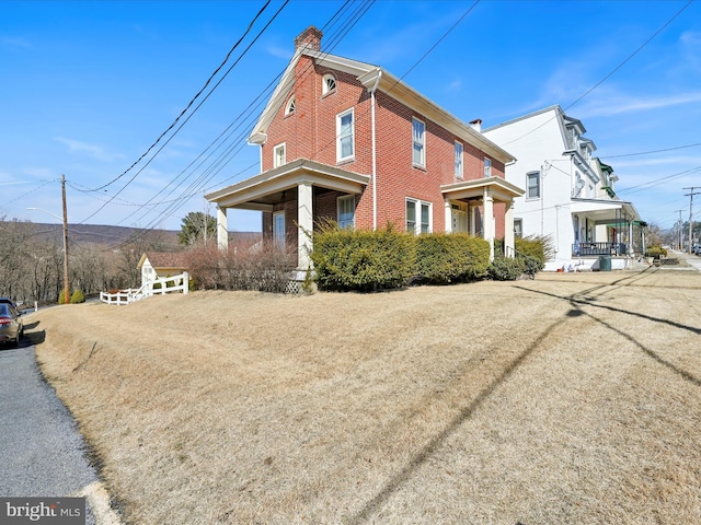 view of front of property with a chimney and brick siding