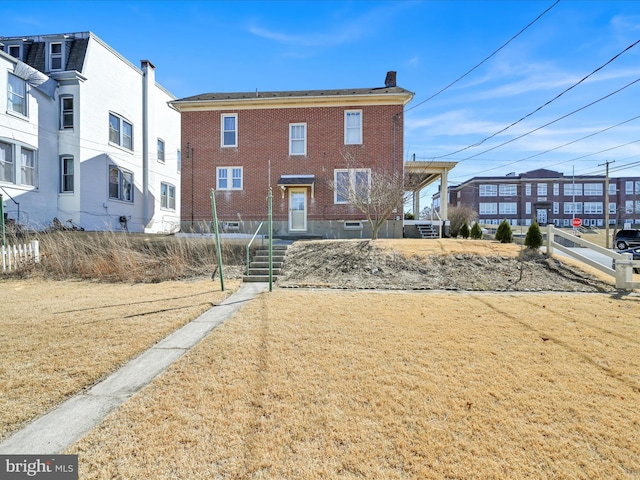 view of front facade featuring brick siding and a chimney