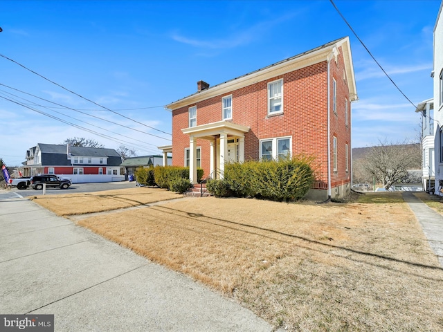 view of front of property featuring a chimney and brick siding