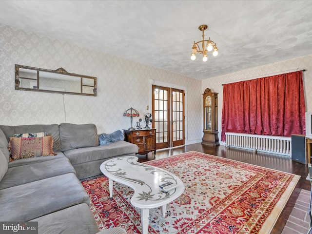 living area featuring french doors, a notable chandelier, radiator, wood finished floors, and wallpapered walls