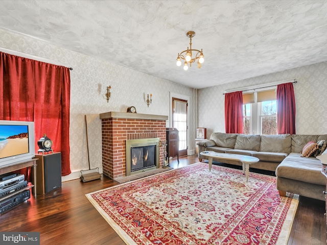 living room with wallpapered walls, a brick fireplace, hardwood / wood-style flooring, and a textured ceiling