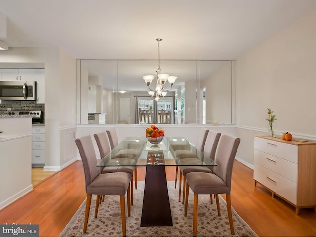 dining space with light wood-style flooring and an inviting chandelier