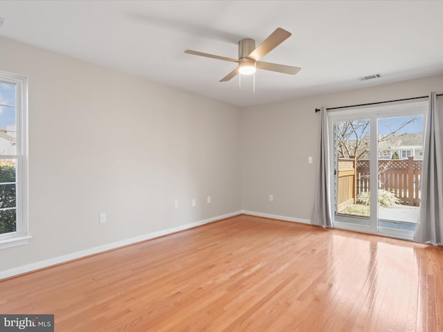 spare room with light wood-type flooring, baseboards, visible vents, and ceiling fan