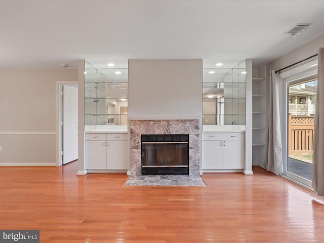 unfurnished living room featuring light wood-type flooring, recessed lighting, visible vents, and a high end fireplace