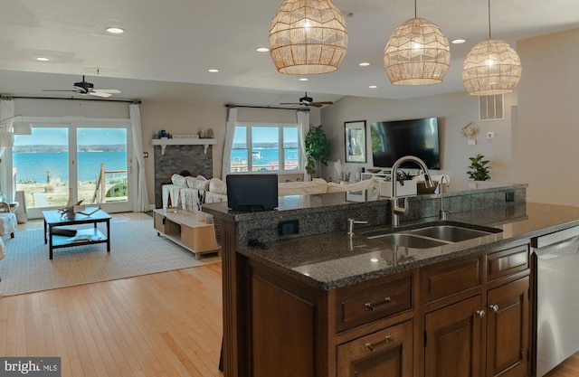 kitchen with a sink, light wood-type flooring, open floor plan, and stainless steel dishwasher