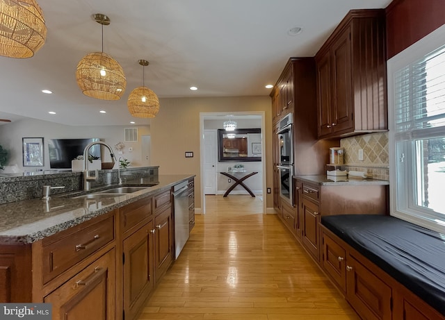 kitchen with pendant lighting, light wood finished floors, stainless steel appliances, tasteful backsplash, and a sink