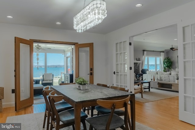 dining room featuring light wood-type flooring, recessed lighting, ceiling fan with notable chandelier, and french doors