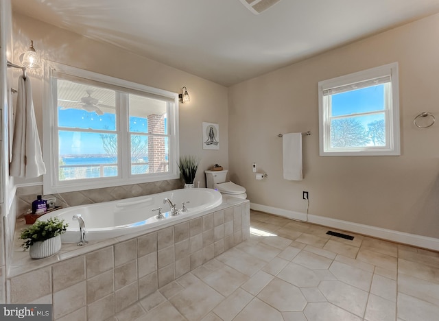 full bath with a wealth of natural light, tile patterned flooring, toilet, and a bath