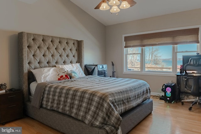 bedroom with ceiling fan, light wood-style flooring, and vaulted ceiling