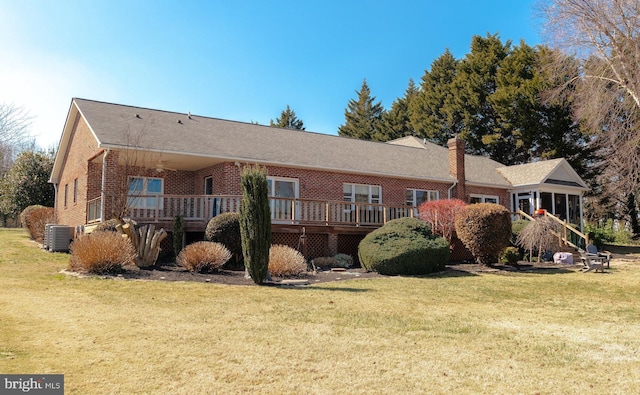 back of house featuring brick siding, a lawn, cooling unit, and a wooden deck