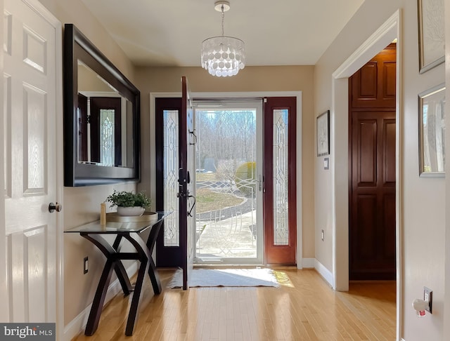 entrance foyer with an inviting chandelier, baseboards, and light wood-style floors