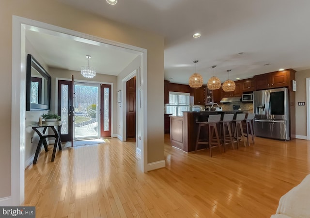 entryway featuring a chandelier, light wood finished floors, plenty of natural light, and baseboards