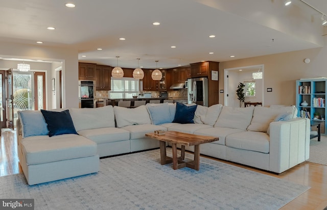 living room with light wood-type flooring, an inviting chandelier, and recessed lighting