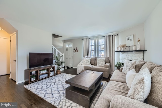 living area with dark wood finished floors, baseboards, and stairs