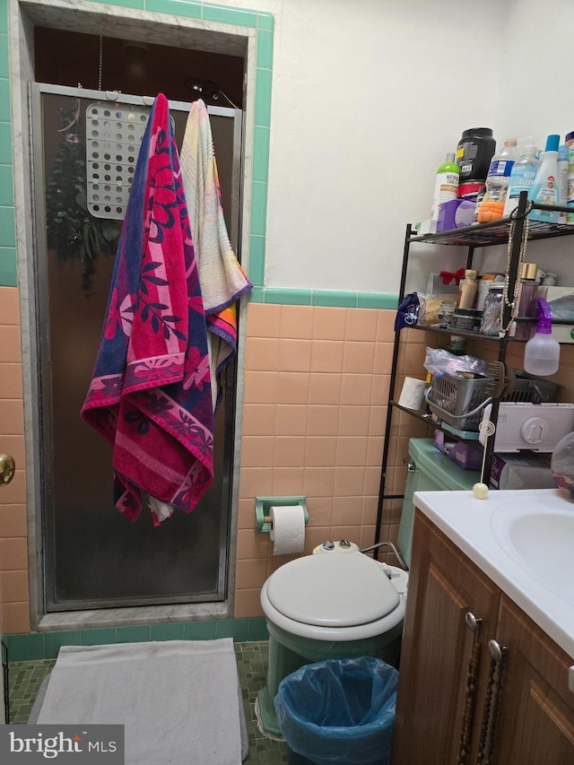 full bath with tile walls, toilet, wainscoting, a shower stall, and vanity