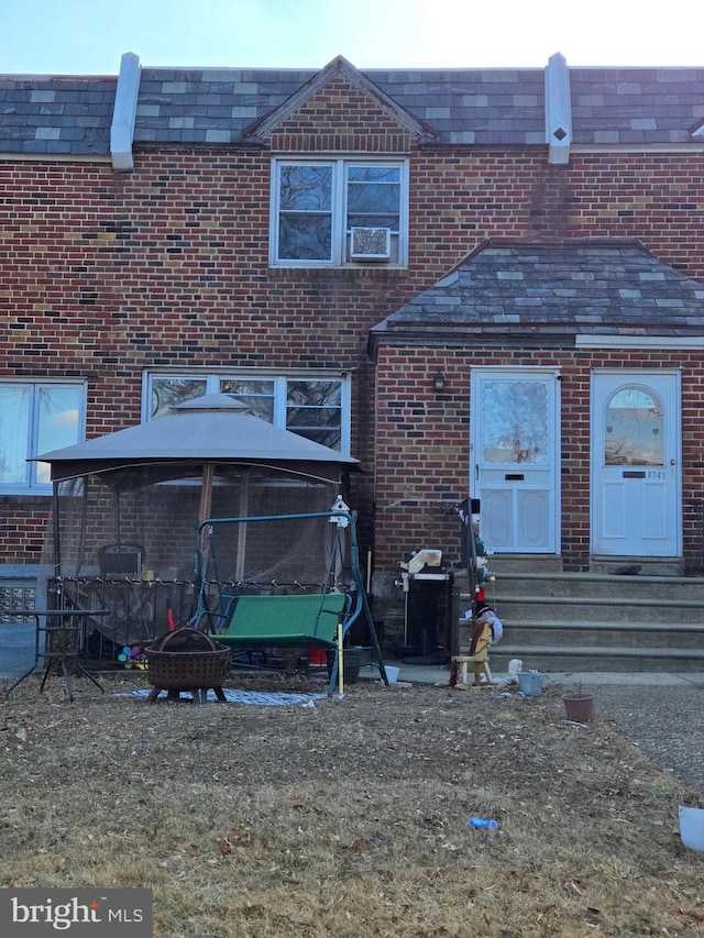 back of house with brick siding and a fire pit