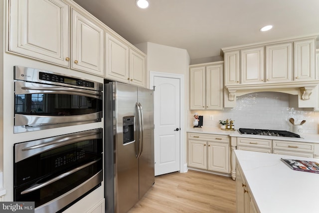 kitchen with decorative backsplash, recessed lighting, light wood-style floors, and stainless steel appliances