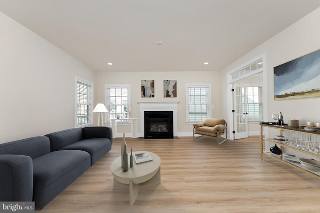 living room with recessed lighting, a fireplace with flush hearth, light wood-style flooring, and baseboards