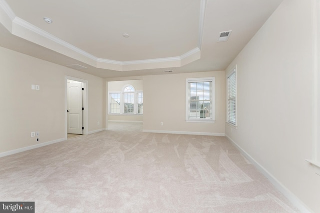 spare room with baseboards, visible vents, a tray ceiling, light carpet, and crown molding