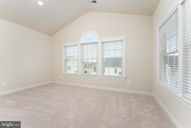 carpeted spare room with a wealth of natural light, visible vents, baseboards, and lofted ceiling