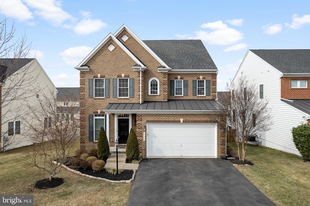 view of front of house with a front yard, driveway, a standing seam roof, an attached garage, and brick siding