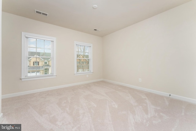 spare room with light carpet, visible vents, and baseboards