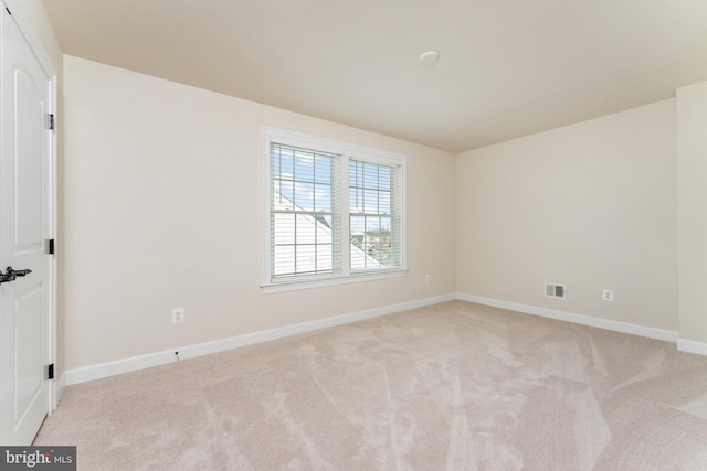 empty room featuring light colored carpet, visible vents, and baseboards