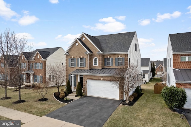 traditional home with a front yard, a standing seam roof, a garage, aphalt driveway, and brick siding