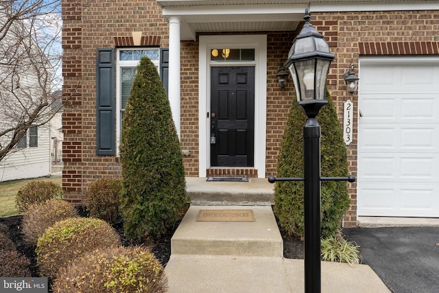 entrance to property with a garage and brick siding