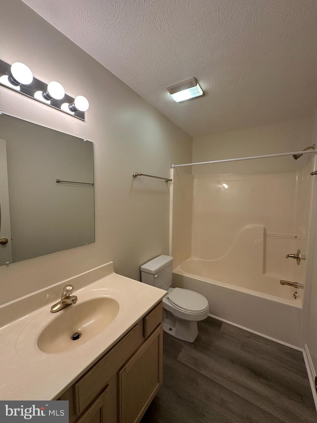 full bath featuring toilet, vanity, a textured ceiling, wood finished floors, and  shower combination