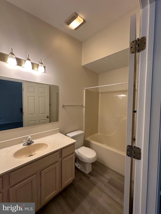 full bath featuring vanity, bathtub / shower combination, wood finished floors, and toilet