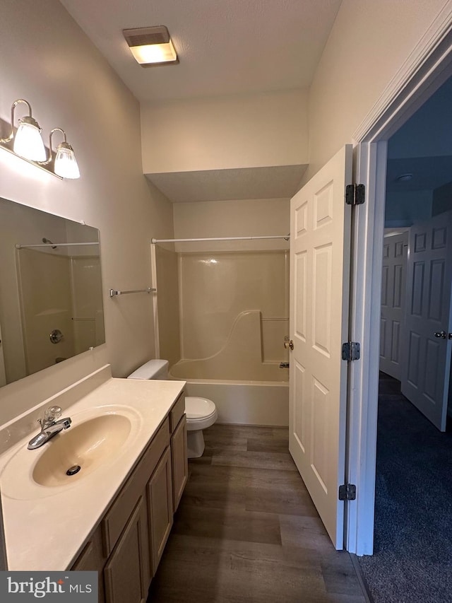 bathroom with toilet, washtub / shower combination, wood finished floors, and vanity