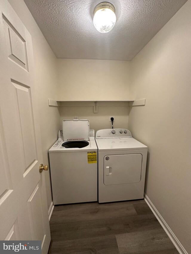 laundry area featuring a textured ceiling, laundry area, baseboards, independent washer and dryer, and dark wood-style floors