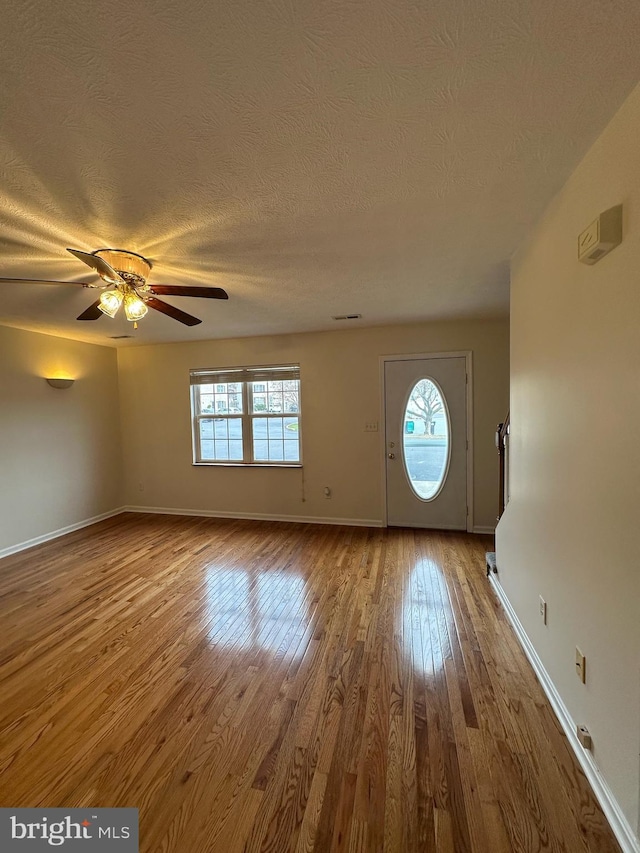 entrance foyer with ceiling fan, a textured ceiling, wood finished floors, and baseboards