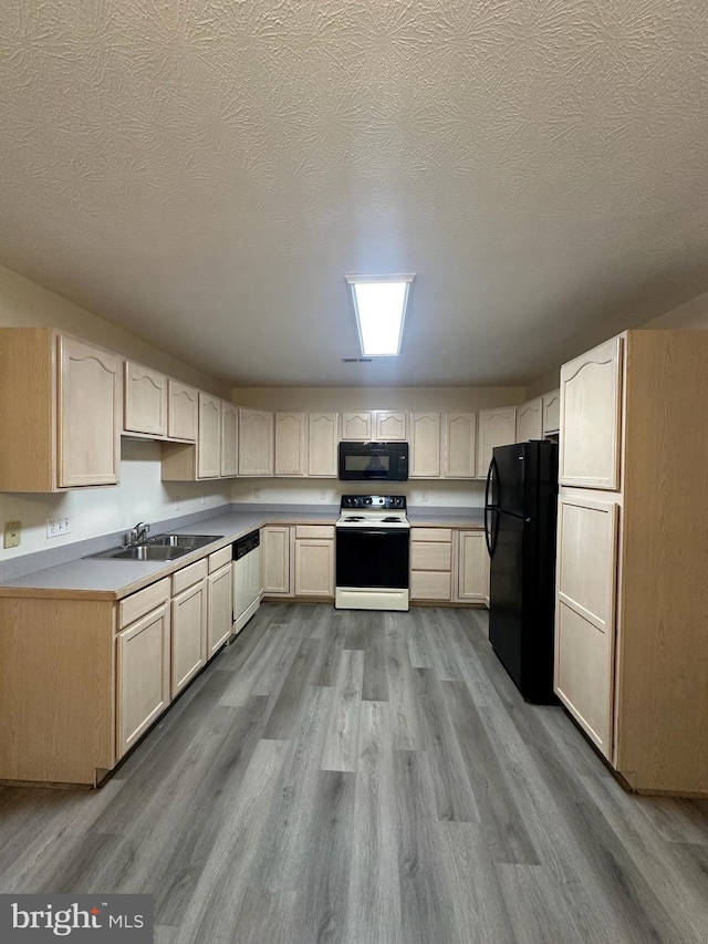 kitchen featuring black appliances, a textured ceiling, a sink, and wood finished floors