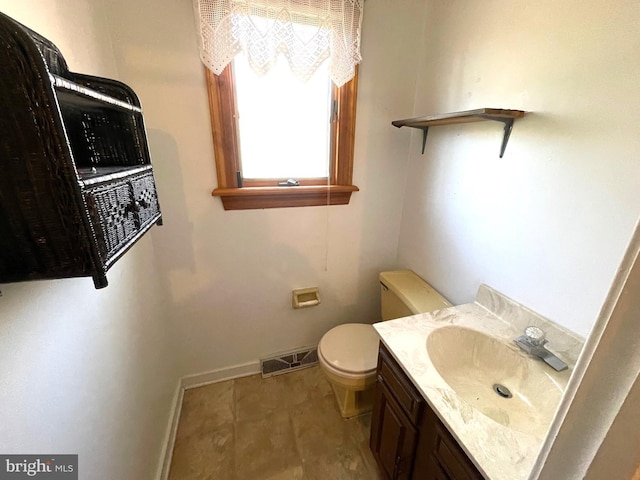 half bathroom with vanity, toilet, baseboards, and visible vents